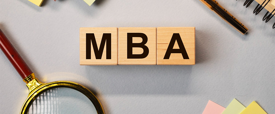 Ξύλινοι κύβοι στη σειρά σχηματίζουν τη λέξη MBA (μεταπτυχιακό στη διοίκηση επιχειρήσεων) πάνω σε γραφείο.