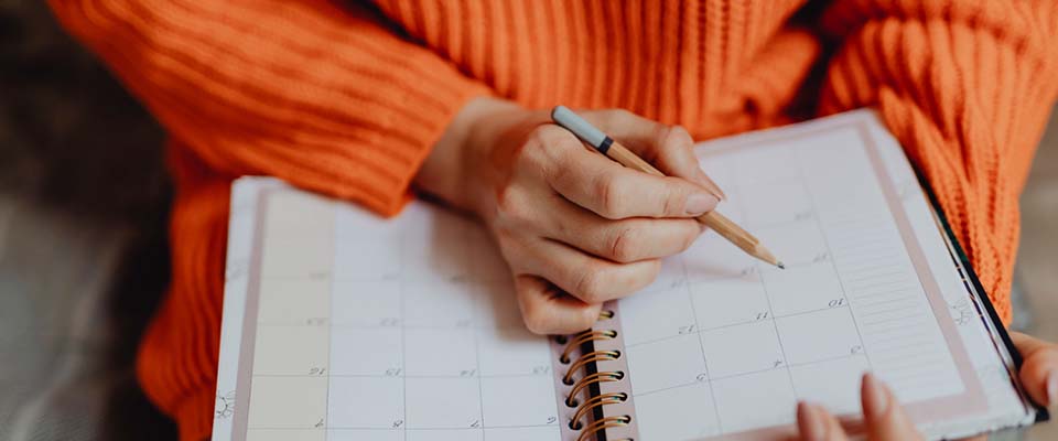 Γυναίκα εφαρμόζει μία συμβουλή διαχείρισης χρόνου, γράφοντας σε ημερολόγιο τις υποχρεώσεις της.