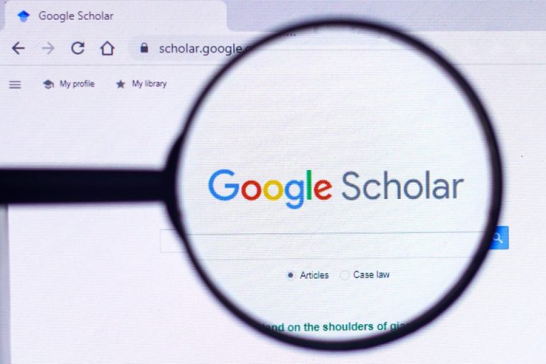 Θεματική εικόνα για το τι είναι το Google Scholar. Η αρχική σελίδα του Google Scholar φαίνεται μέσα από μεγεθυντικό φακό.